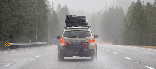 Car driving on highway on foggy day with roof cargo.