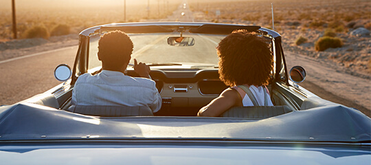 A couple riding in a classic convertible.