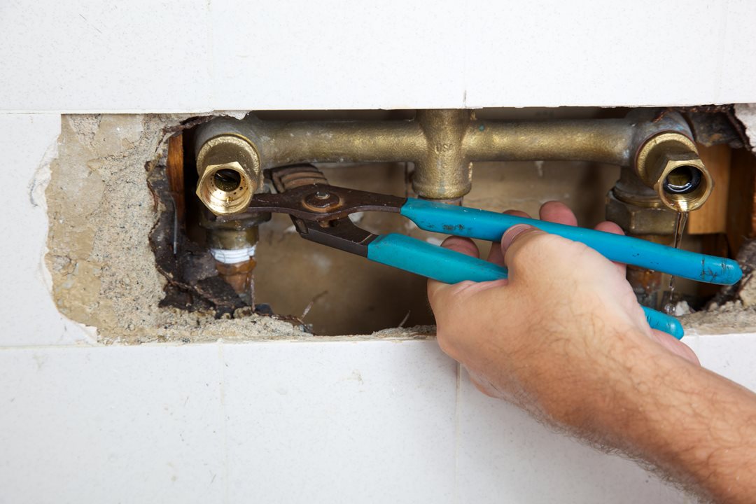 Tightening a water pipe with a wrench.